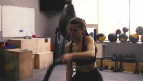 Starkes,-Sportliches-Brünettes-Mädchen-In-Den-Zwanzigern,-Das-Im-Fitnessstudio-Battle-Ropes-Training-Durchführt.