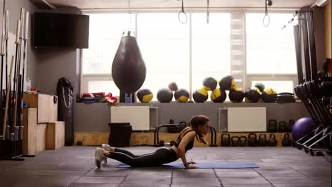 Sportive-attractive-brunette-girl-doing-fat-burning-set-of-exercises-in-the-gym-on-floor-mat.-Fitness-and-healthcare.