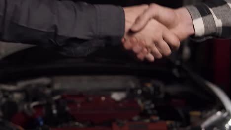 Close-Up-shot-of-mechanic-and-customer-shaking-hands-in-an-auto-repair-shop.
