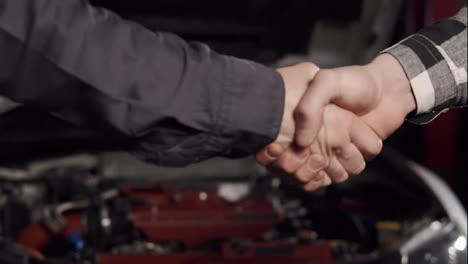 Close-Up-shot-of-mechanic-and-customer-shaking-hands-in-an-auto-repair-shop.