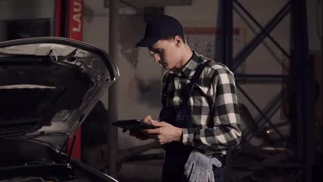 Car-service-technician-using-digital-tablet-to-examine-the-vehicle-insides.