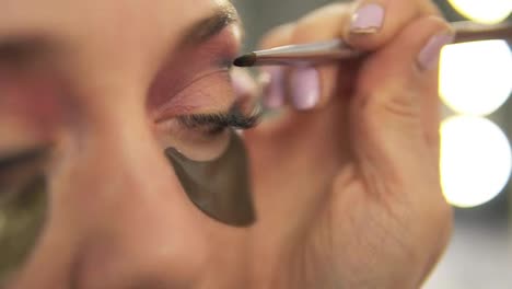 Make-up-artist-applying-eye-shadow-to-model's-eye.-Close-up-view.-Patches