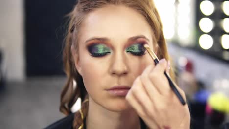 Make-up-stylist-finished-green-smokey-eyes-make-up-for-fair-hair-model.-She-slowly-open-her-eyes.-Front-view.-Slow-motion