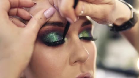 Final-touches-of-visagist-work-to-complete-green-eyes-make-up-for-a-gourgeous-woman.-Shine-shadows