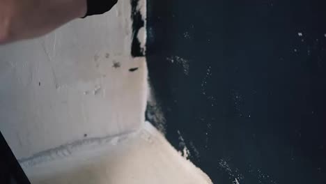 Young-woman-with-paint-roller-carefully-paints-the-wall-with-black-colour