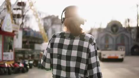 Tracking-shooting-of-a-young,-brown-haired-girl-walking-on-the-street-in-sunny-day-with-a-headphones.-Dancing-and-whirling.-Happy-and-carefree