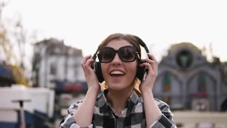 The-girl-is-putting-on-the-headphones-and-starting-to-move-with-the-rhythms-of-the-music.-In-sunglasses.-Enjoy-it.-Slow-motion