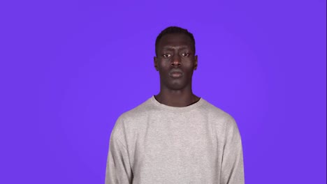 Portrait-of-young-serious-man-staring-at-camera-with-crossed-arms-protesting.-Beautiful-african-black-man-in-white-sweatshirt-on-blue-background