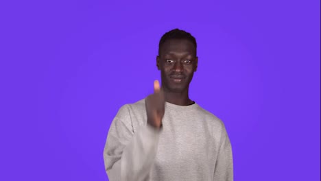 A-smiling-positive-young-african-american-man-in-white-sweater-is-doing-a-thumb-up-gesture-isolated-over-blue-wall-background-in-studio