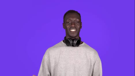 Attractive-joyful-young-african-man-looking-to-the-camera-in-headphones-on-neck-smile-happy-talks-at-camera.-Positive-emotions.-Male-portrait.-Contemporary-human