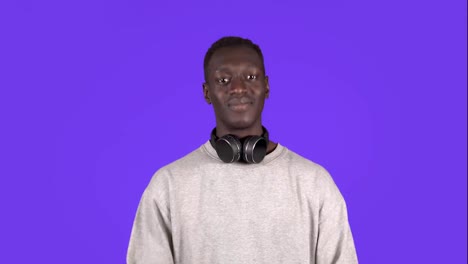 An-attractive-young-man-with-headphones-on-neck-in-a-white-shirt-is-nodding-his-head-positively-isolated-over-blue-background