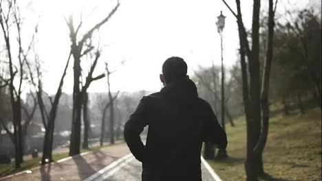 Backside-footage-of-male-figure-running-in-park.-Slow-motion.