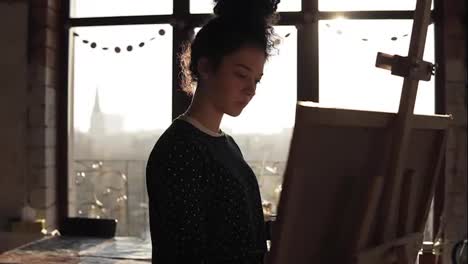 Slow-motion-footage-of-a-cute-female-artist-in-her-20's-drawing-on-easel.