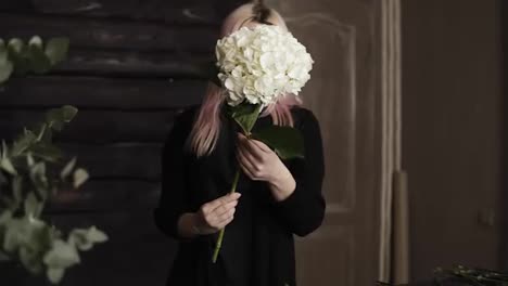 Pink-haired-beautiful-florist-holding-in-hands-giant-white-hydrangea-flower.-Takes-off-extra-leaves