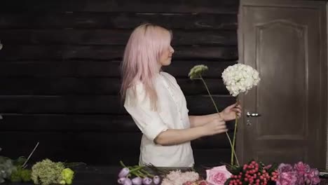 Happy,-beautiful-girl-florist-in-a-white-shirt-enthusiastically-chooses-flowers-for-a-composition-from-a-wide-assortment-of-flowers.-Slow-motion