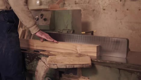 Close-up-footage-of-man-in-work-clothes-working-on-electric-saw-with-wooden-material-in-carpentry.-Slow-motion