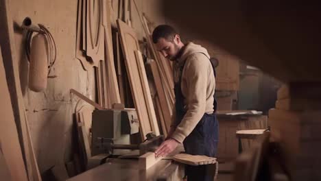 Craftman-in-a-blue-overalls-cuts-the-rail-on-a-circular-saw-and-turns-off-the-machine.-Slow-motion.-Workshop