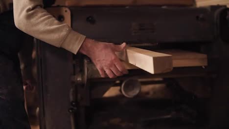 Closeup-of-a-male-hand-pushing-a-wooden-rail-through-a-stationary-grinding-machine.-Slow-motion