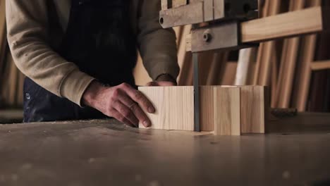 Close-up-view-of-a-carpenter-cutting-a-wood-into-pieces.-Works-with-electric-saw-machine.-Wood-dust-on-the-surface