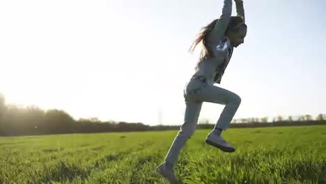 Long-haired-little-girl-in-white-clothes-is-playing-outdoors.-She-does-somersaults.-A-large-green-meadow.-Fun-and-carefree