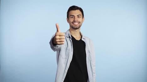 Happy-man-shows-thumb-up,-joyful-man-smiling-to-the-camera.-Cheerful-brunette-guy,-successful-guy-giving-thumb-up-successful-thumb-up-yes-ok-concept-caucasian-adult-man-model-on-the-blue-background