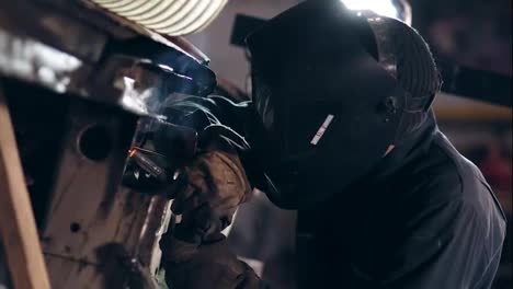 Male-worker-at-a-welding-factory-in-a-welding-mask.-Welding-on-an-industrial-plant.-Slow-motion.