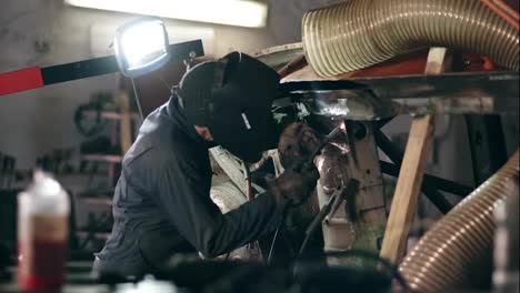 Male-worker-at-a-welding-factory-in-a-welding-mask-is-working-with-metal-construction.-Welding-on-an-industrial-plant.-Slow-motion.