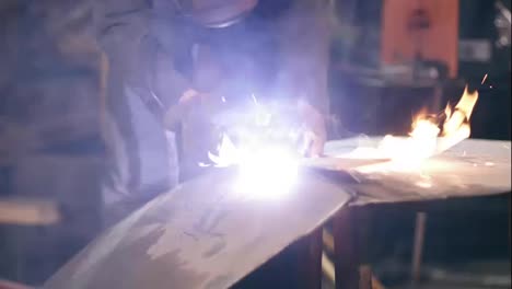 Male-worker-in-protective-gloves-and-workwear-is-cutting-off-metal-piece-with-oxy-acetylene-cutting-torch-at-a-factory.-Slow-motion-footage.