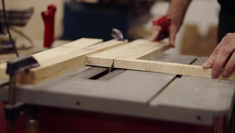 Front-view-footage-of-cutting-wooden-board-on-saw-machine.-Action.-Industrial-machine-with-circular-saw-cuts-wooden-board.-Male-hands-gently-pushing-a-pattern-to-a-circular-disk