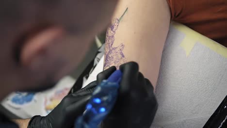 Close-up-footage-of-tattoo-artist-demonstrates-the-process-of-getting-colour-tattoo.-Animalconcept.-Modern-tattoo-parlor.-Top-view-of-tattoo-artist-and-his-female-client-in-a-beauty-salon