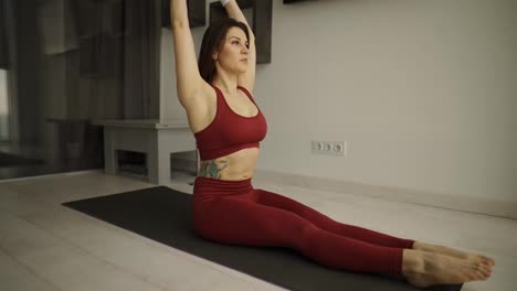 Woman-doing-abdominal-exercise-with-dumbbells-in-her-hands-on-a-mat-on-the-floor-in-the-living-room