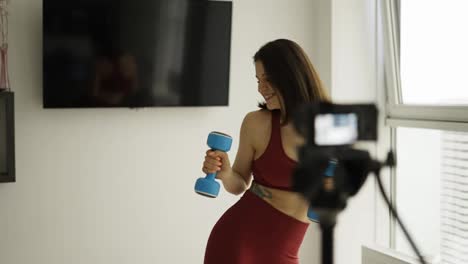 Woman-fitness-instructor-records-a-tutorial-training-while-dancing-with-dumbbells