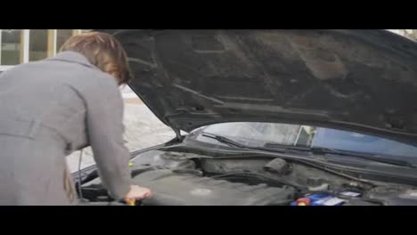 Business-woman-checks-the-oil-level-in-the-car-looking-under-the-hood-in-the-street