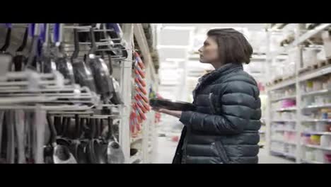 Young-woman-shopping-in-grocery-chosing-frying-pan