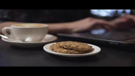Tasse-Kaffee-Und-Kekse.-Frau-Arbeitet-Mit-Laptop-Im-Hintergrund