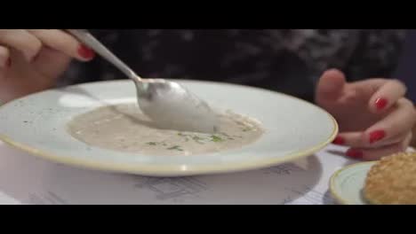 Cooling-soup-with-spoon-close-up.Person-hand-with-spoon-mixing-hot-soup.
