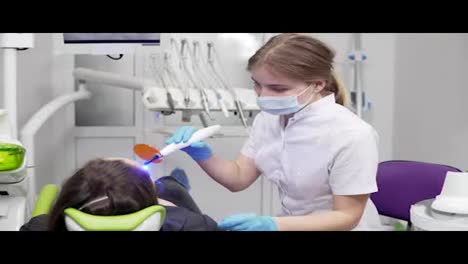 Junge-Zahnärztin-In-Maske-Und-Handschuhen,-Die-Zahnärztliche-UV-Lichtgeräte-Zur-Polymerhärtung-Verwendet