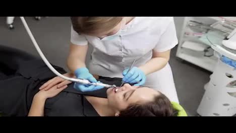 Joven-Dentista-Con-Guantes-Y-Máscara-Perforando-Los-Dientes-Del-Paciente-En-La-Clínica