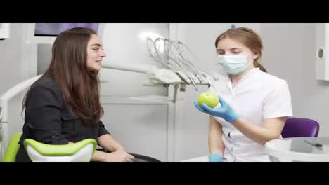 Junge-Zahnärztin,-Die-Glücklichen-Und-Gesunden-Patienten-Nach-Den-Eingriffen-Grünen-Apfel-Anbietet