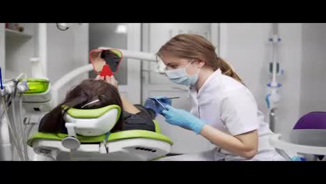 Estomatología.-Una-Joven-Dentista-Está-Hablando-Con-Un-Cliente-Y-Dándole-Un-Espejo.