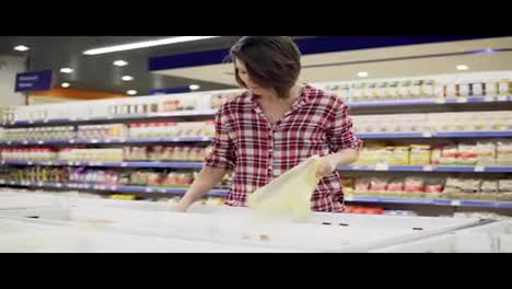 Joyful-brunette-woman-buying-groats-by-weight-in-supermarket