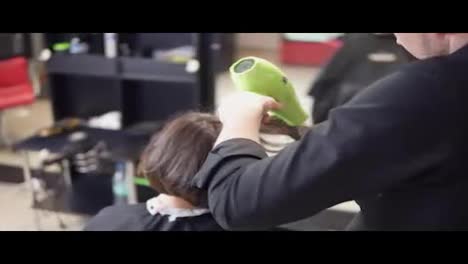 Professional-hairdresser-is-drying-hair-of-young-attractive-woman-in-beauty-salon.-Shot-in-4k