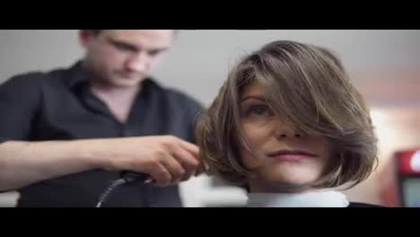 Hair-stylist-makes-professional-hairstyle-of-young-woman-in-beauty-studio.-Hair-straightening.