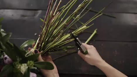 Beautiful-female-hands-cut-the-stems-of-flowers-with-a-pruner-on-a-dark-surface.-Floral-studio.-Top-shot