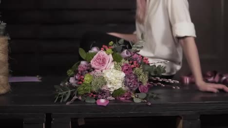Beautiful-slow-motion-footage-of-an-amazing-bouquet-made-by-professional-florist.-Seductive,-smiling-girl-in-white-shirt-is-sitting-on-the-table.-Studio