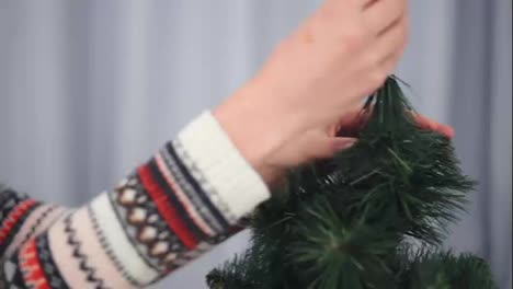 Young-happy-woman-decorating-a-Christmas-tree-taking-a-silver-star-and-hanging-it-on-the-top-of-the-tree.-Shot-in-4k