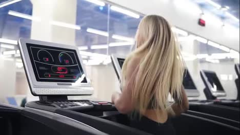 Young-attractive-caucasian-woman-with-blond-hair-in-black-sport-outfit-running-on-treadmil-at-the-gym-in-slomo