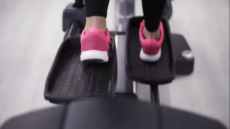 Female-legs-in-pink-sneakers-pedaling-on-an-orbitrek-simulator-close-up