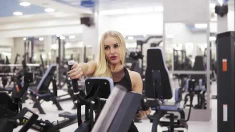 Young-female-bodybuilder-in-black-sportswear-doing-exersices-at-the-gym.-Building-up-strong-core-and-arms-muscles