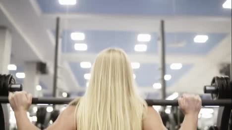 Young-beautiful-blond-female-doing-squats-with-barbell.-Doing-excercises.-Weightlifting.-Healthy-lifestyle-concept.